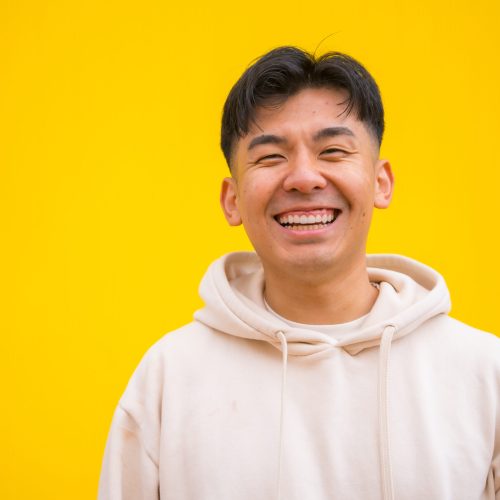 Portrait of a handsome Asian man in basic clothes smiling isolated over yellow background Portrait of a handsome Asian man in basic clothes smiling isolated over yellow background